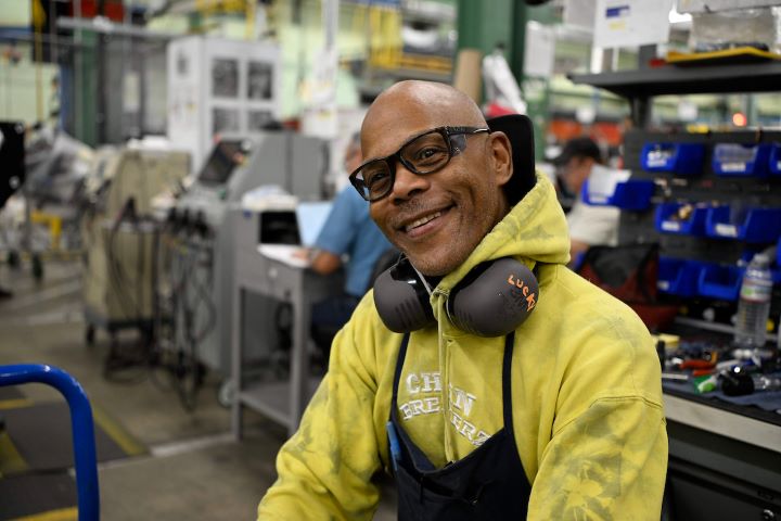 An S&C team member wearing personal protective equipment smiles at the camera