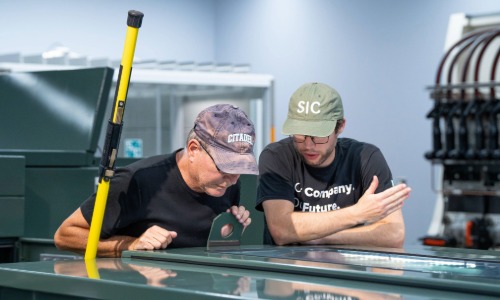 two men discussing over equipment on manufacturing day